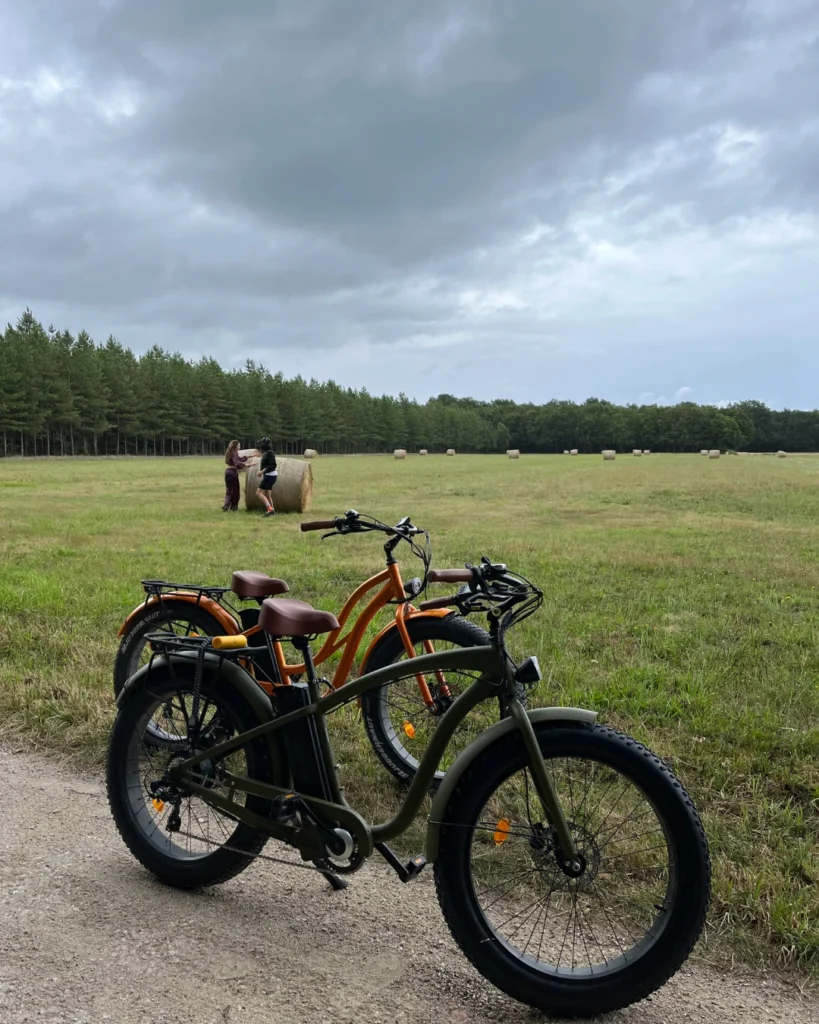 Deux fat bikes stationnés en bord de champ avec des bottes de foin, prêts pour une randonnée en pleine nature.